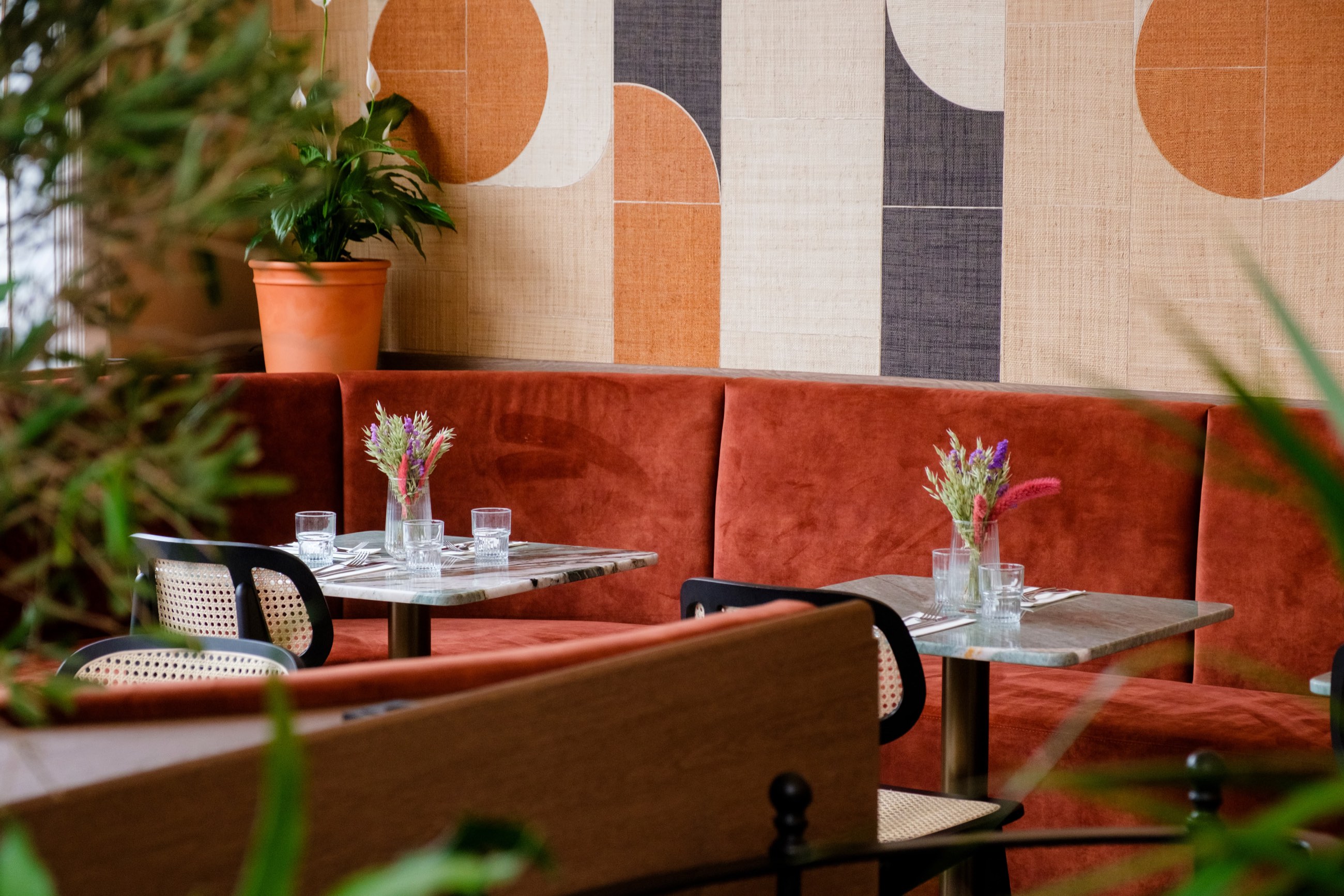 The Solon Bistro — cane chairs and marble tables against the rust banquette and the tiled wall behind it.