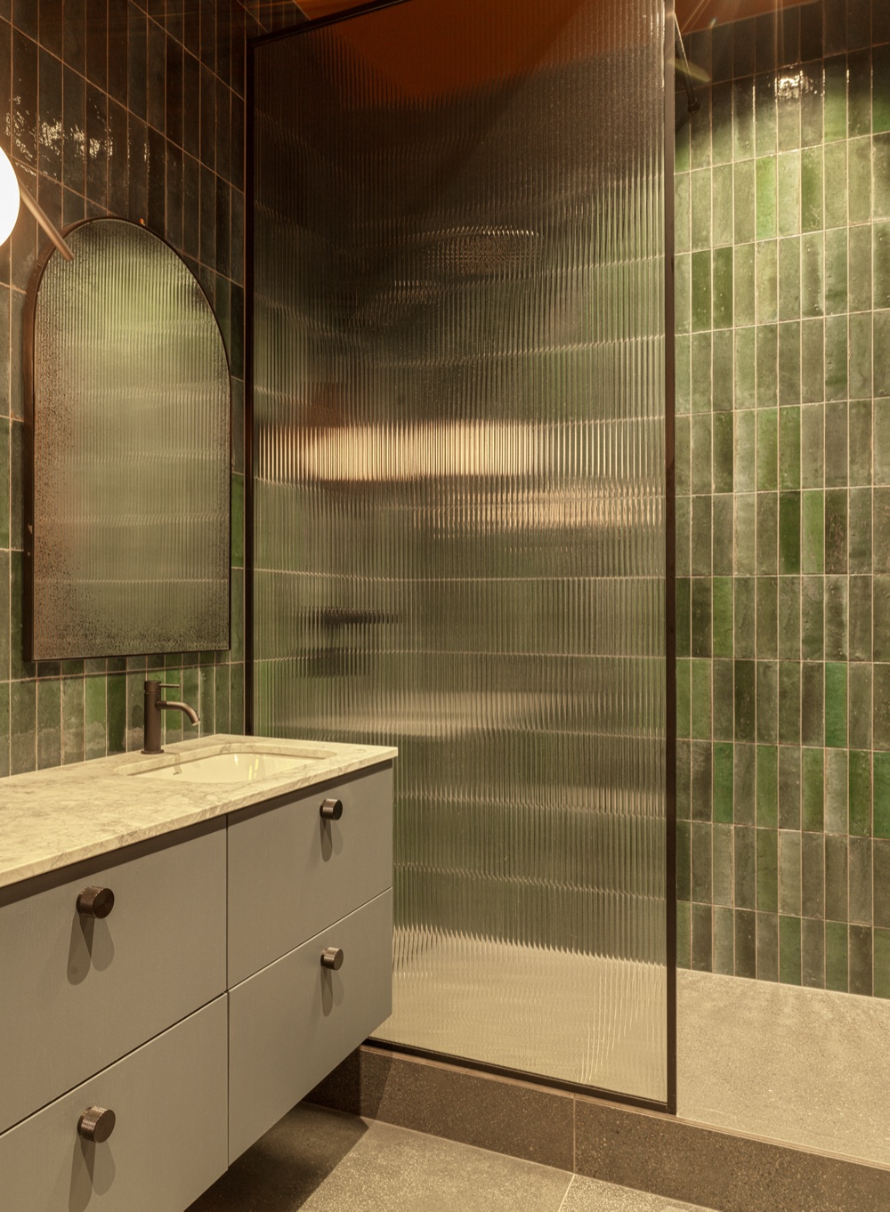 Hanna Thor — a green-tiled bathroom with ribbed glass and a marble vanity.