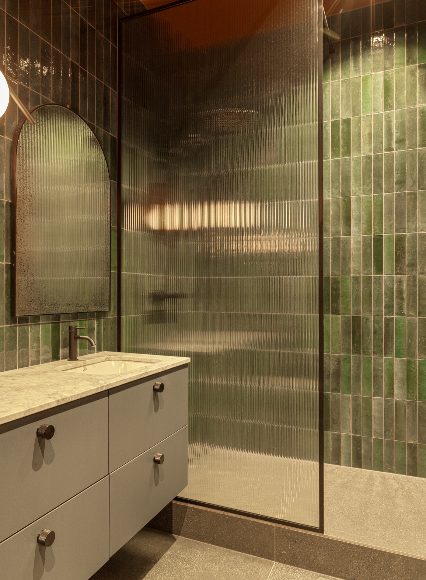 Hanna Thor — a green-tiled bathroom with ribbed glass and a marble vanity.