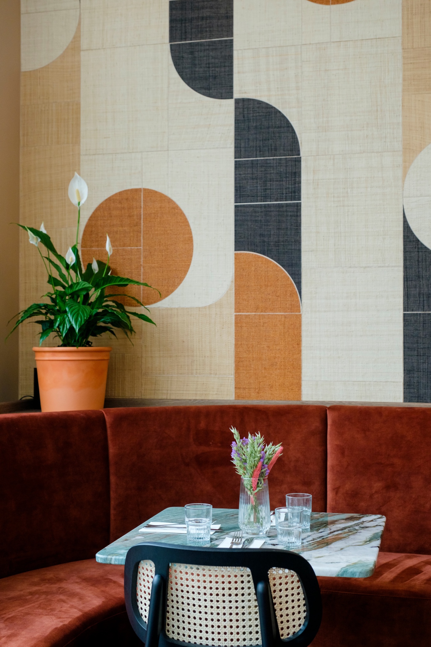 The Solon Bistro — a rust banquette beneath a graphic woven wall hanging.