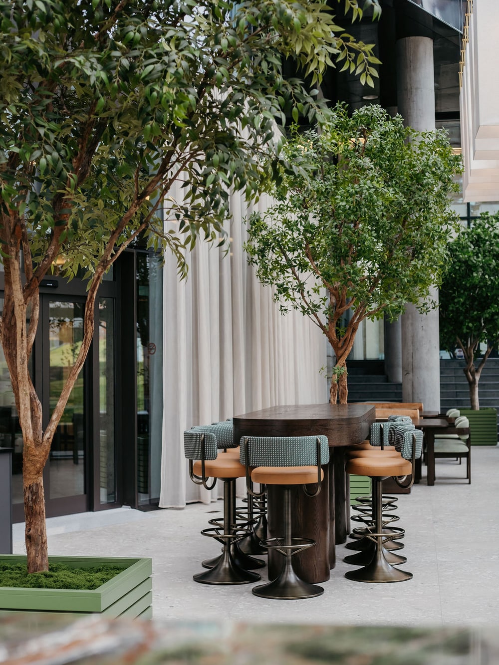 Höfðatorg — bar stools and planted trees on the terrace