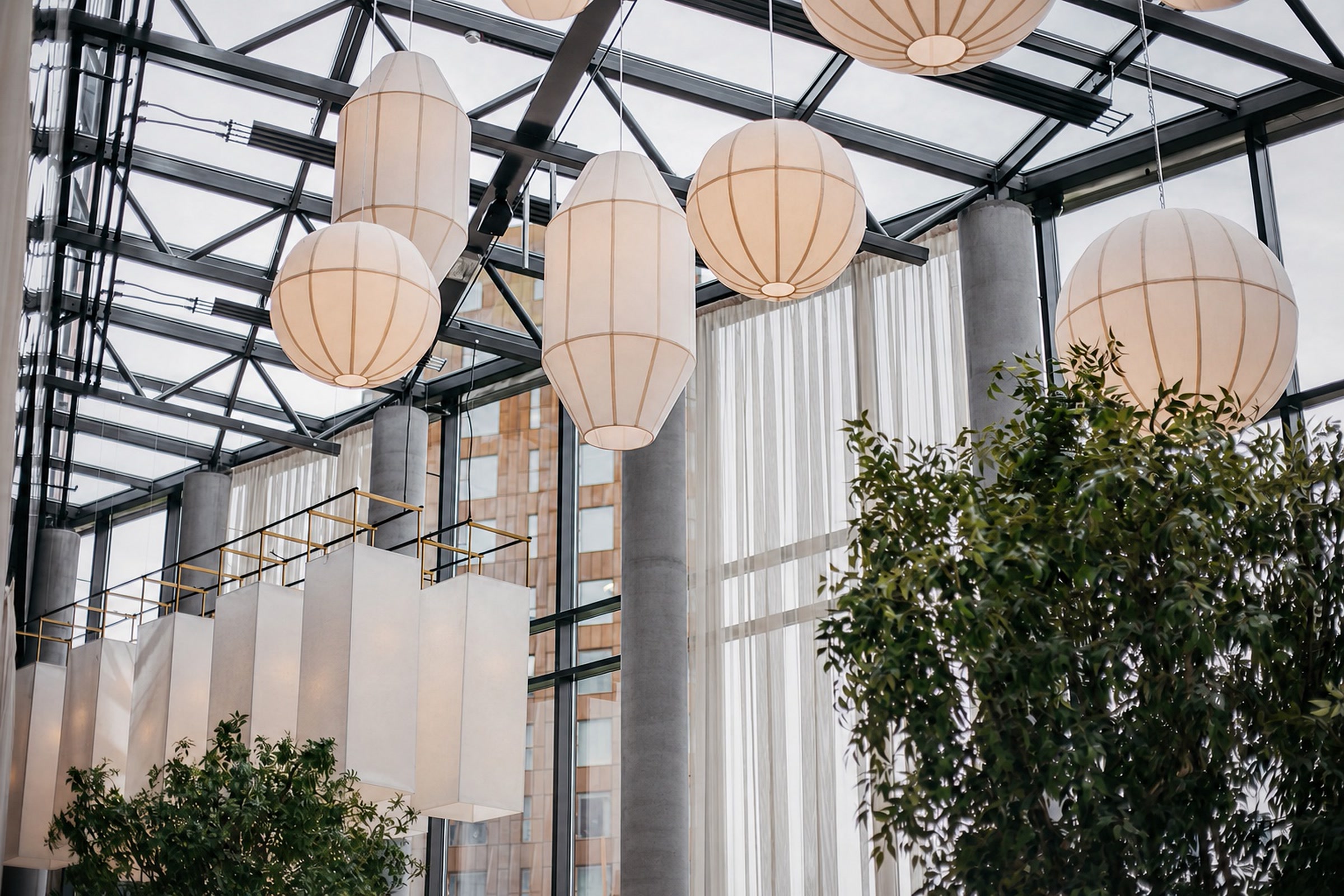 Höfðatorg — sculptural pendant lights and planting beneath a glazed steel roof.