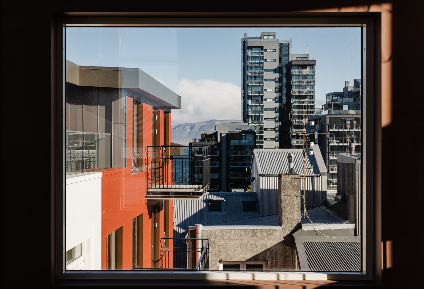 The Reykjavik Residence — Reykjavík rooftops and a distant mountain ridge framed by a window reveal.
