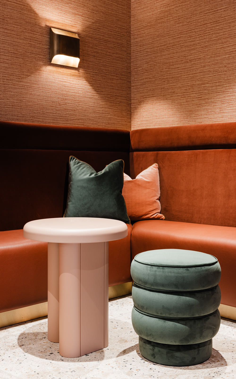A corner banquette at the Reykjavík Residence, terracotta walls and green velvet stools.