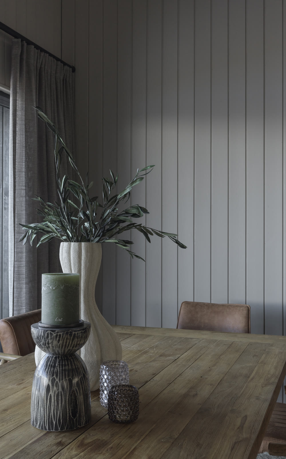 The dining table at Meðalfellsvatn — olive branches in a pale vase against a panelled wall.